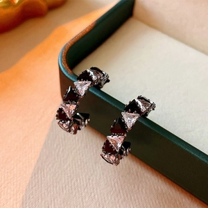 Macro detail of C-shaped earrings with triangular black and white cubic zirconia