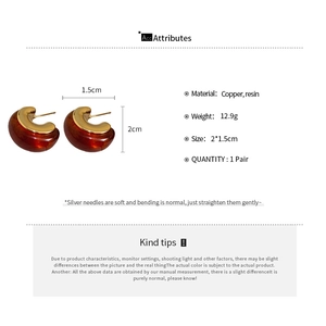 Detailed view of C-shaped earrings made of gold-plated copper and reddish resin