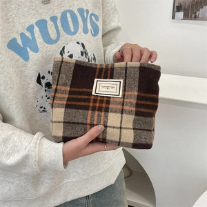 Close-up of vintage plaid wool pouch featuring a white woven label and soft fabric texture