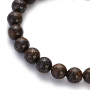 Macro detail of natural stone beads with deep brown textures on a minimalist bracelet