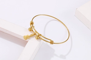 Detail of adjustable gold steel bracelet featuring guitar pendant and beads on white props