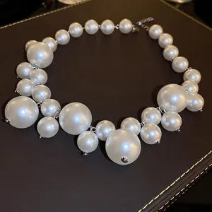 Elegant multi-size pearl necklace with silver lobster clasp on brown leather background