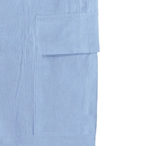 Détail du pantalon cargo en lin bleu clair montrant le rabat de la poche