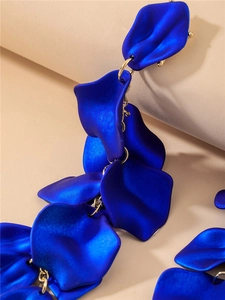 Détail des pétales bleus mats avec chaînes dorées sur les boucles d'oreilles pendantes