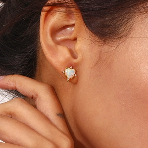 Close-up of heart-shaped opal stud earring with gold plating and zircon accents
