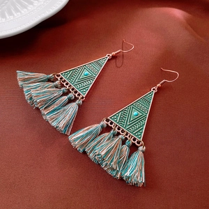 Macro view of vintage tassel earrings featuring geometric metal studs and silk backdrop