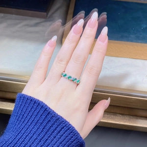 Detail of S925 silver ring featuring alternating emerald green and clear stones on finger