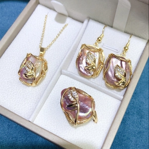 Detail of pink baroque pearl jewelry set with leaf design in a beige leather box