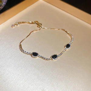 Detail of adjustable gold bracelet with black oval stones and shimmering white zircons