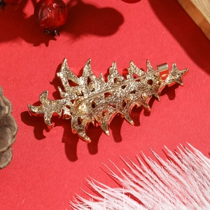 Golden Christmas tree brooch with intricate cutout back on a festive red background