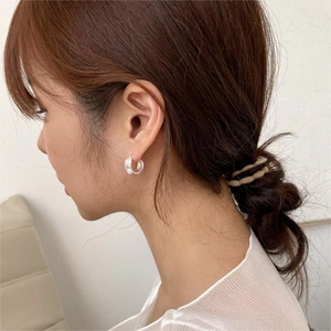 Close-up of elegant pearl drop earrings worn by a model, showing lustrous silver finish