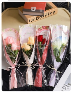 Detailed view of four colorful single rose bouquets in stylish romantic floral packaging