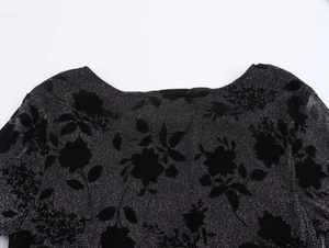 Close-up of elegant black knit dress neckline featuring silver glitter and velvet floral patterns
