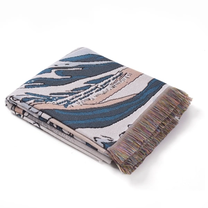 Detail of woven bohemian throw blanket with abstract sea wave pattern and colorful fringe