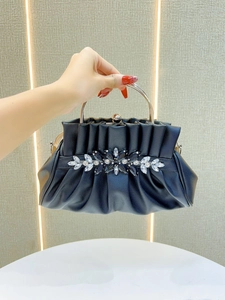 Close-up of black pleated evening bag with sparkling rhinestone flower and metal handle