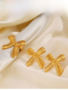 Detail of 18K gold-plated bow jewelry set with textured matte finish on satin fabric