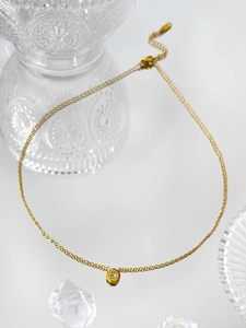 Close-up of a 18K gold-plated necklace with a zircon pendant on crystal background