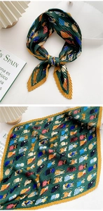 Detailed view of pleated green silk scarf with yellow edges and cartoon cat prints