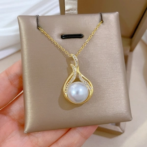 Detailed macro view of a gold fishtail necklace featuring a central pearl and pave diamonds