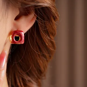 French vintage square hollow hoop earrings with deep red enamel and gold finish on a model