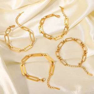 Flat lay of four 18K gold-plated stainless steel bracelets on elegant cream silk fabric