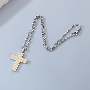 Close-up of dual-tone cross pendant with gold matte finish and silver rolo chain