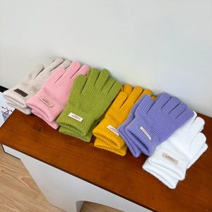 Detailed view of colorful knit gloves with ribbed cuffs and decorative brand labels