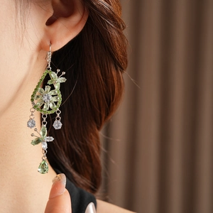 Close-up of elegant silver drop earrings with green zircon flower and butterfly design
