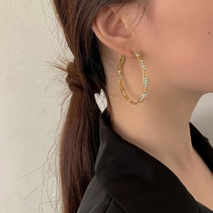 Macro side view of large gold-tone geometric hoop earrings with sparkling rhinestones