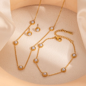 Detailed view of a gold-plated stainless steel jewelry set with pearls on satin cloth