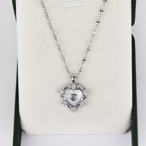 Close-up of a layered heart pendant necklace with shell inlay and diamonds in a green box