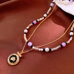Détail du collier superposé vintage plaqué or avec pendentif rose et perles colorées