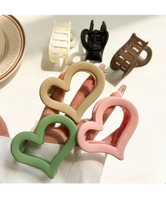 Detailed close-up of matte heart-shaped acrylic hair claws in assorted neutral colors