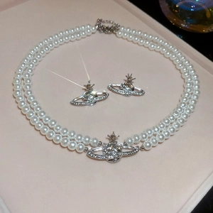 Detail view of double-layer pearl necklace with crystal Saturn pendant and matching studs