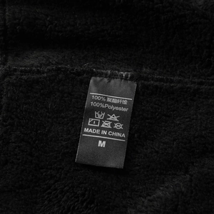 Detailaufnahme der Fleece-Stoffstruktur und des Pflegeetiketts der schwarzen Hose