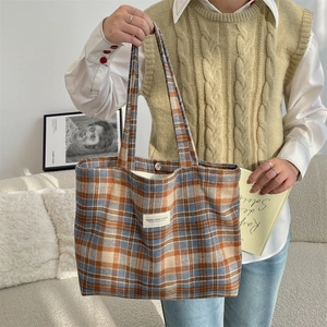 Detail of vintage plaid wool tote bag showing retro checkered fabric and button closure