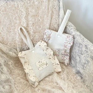 Detailed macro view of quilted cotton wristlet bag with floral ruffle edge and snap closure