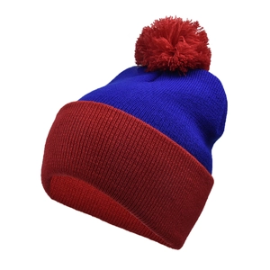Detail of knit winter hat featuring blue ribbed texture and large red pom-pom decoration