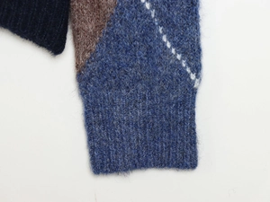 Detailed close-up of fuzzy argyle knit sweater cuffs with soft navy blue ribbed texture
