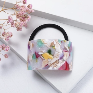 Close-up of acetic acid hair tie with colorful marble texture on minimalist white background
