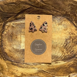 Detail of Christmas tree earrings with leopard print and gold foil on display card
