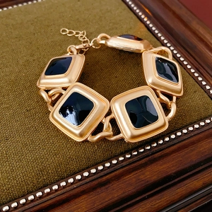 Detail of vintage gold bracelet with black square links on green fabric inside a wooden box