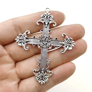 Macro detail of gothic cross pendant with pentagram star on palm with white background