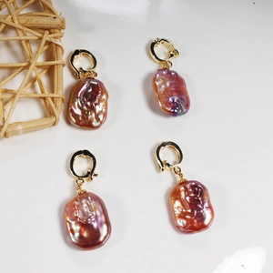 Gold hoop earrings with large baroque pearls featuring purple and pink iridescent luster