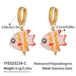 Macro shot of colorful ceramic fish earrings with golden stainless steel hoops details