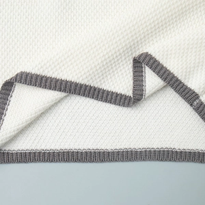 Macro detail of white waffle knit fabric with grey ribbed hem stitching on the vest edge