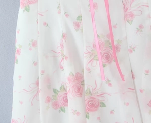Detail of floral chiffon fabric with pink roses and delicate satin ribbon accents