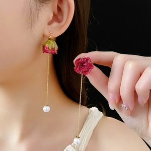 Vue détaillée des boucles d'oreilles rose éternelle rouge avec perles blanches