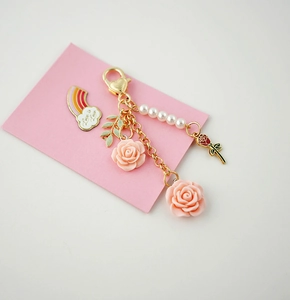 Detail of keychain with pink roses, pearls, and rainbow Love is Love brooch pin