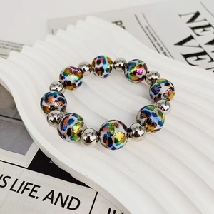 Detailed close-up of a vibrant laser leopard print beaded bracelet on a wavy white plate